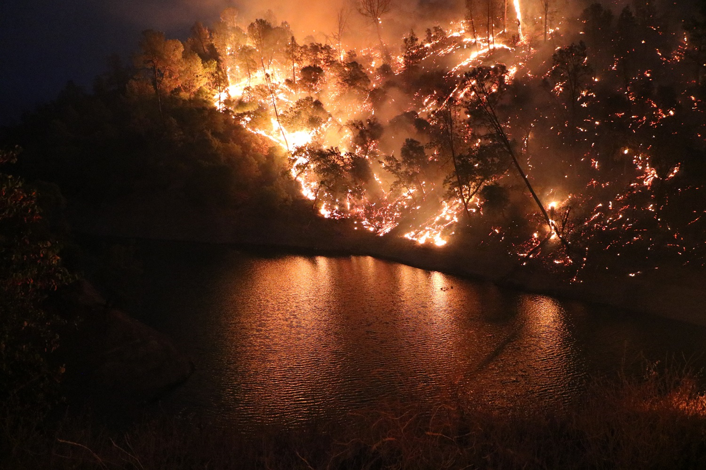 Flames burn towards a lake during the LNU lightning complex