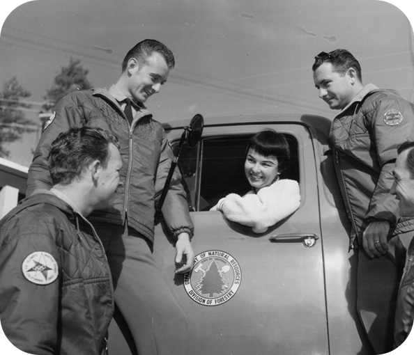 An image from the 1960's showing three CDF employees speaking to a woman in a fire truck