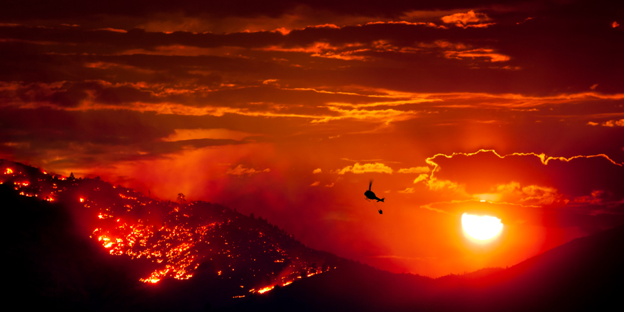 burning hillsides with a helicopter working the fire