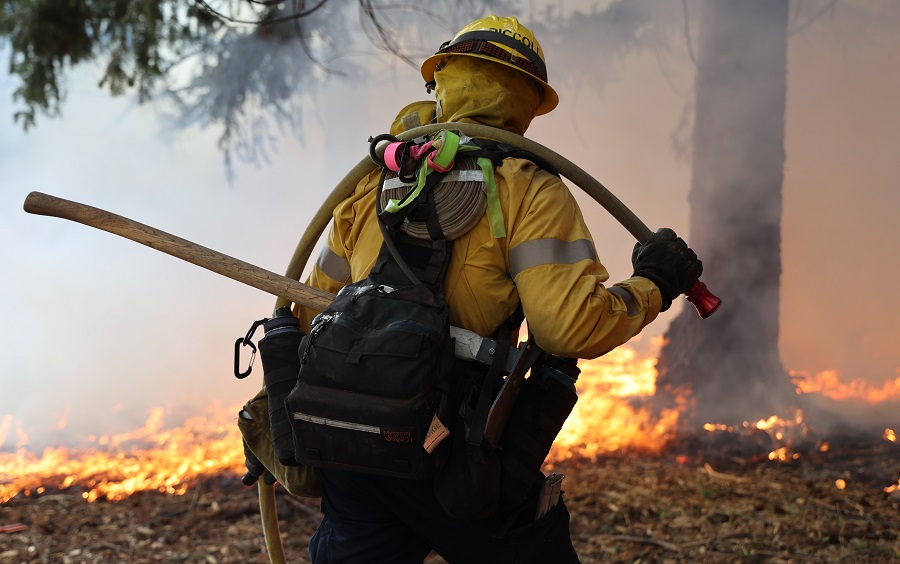 Seasonal Fire Fighter carrying hose and other PPE to the fire front. 