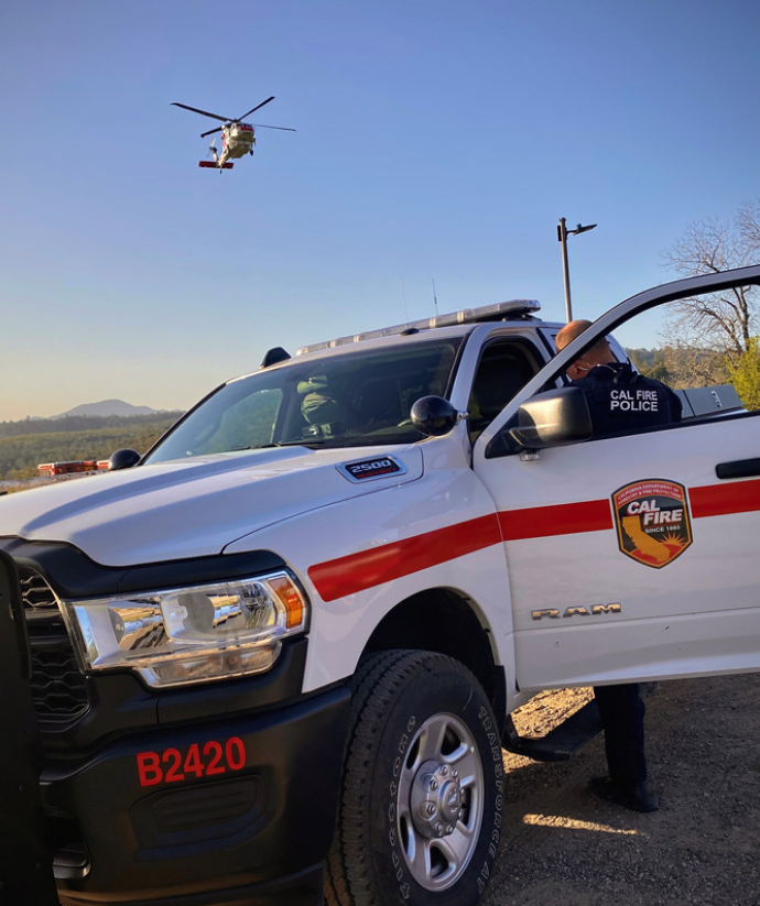 A CAL FIRE law enforcement officer leans into his vehicle