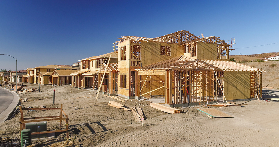 A subdivision, multiple houses along a street, under construction