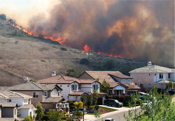 Housing being threatened by a fire crossing over a hill